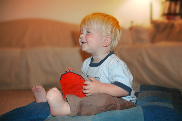 dítě sedící na velkém modrém polštáři s blonďatými vlasy